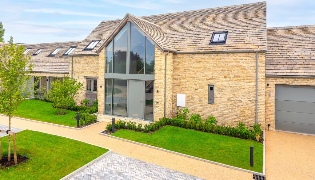 Large beige brick house with glass front and grey doors and windows