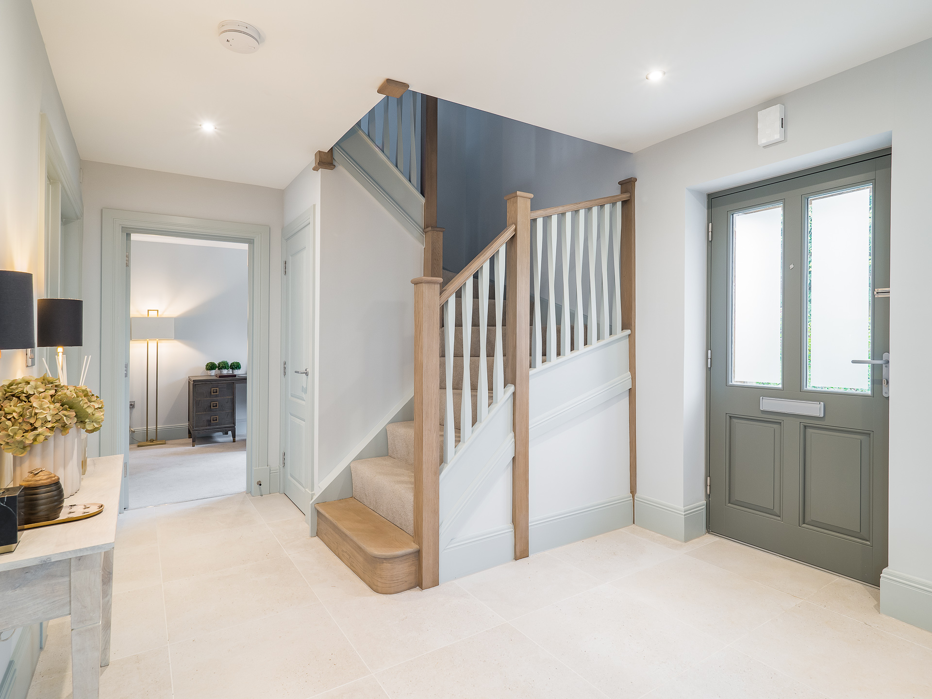Entranceway with dark grey front door and curved stairs
