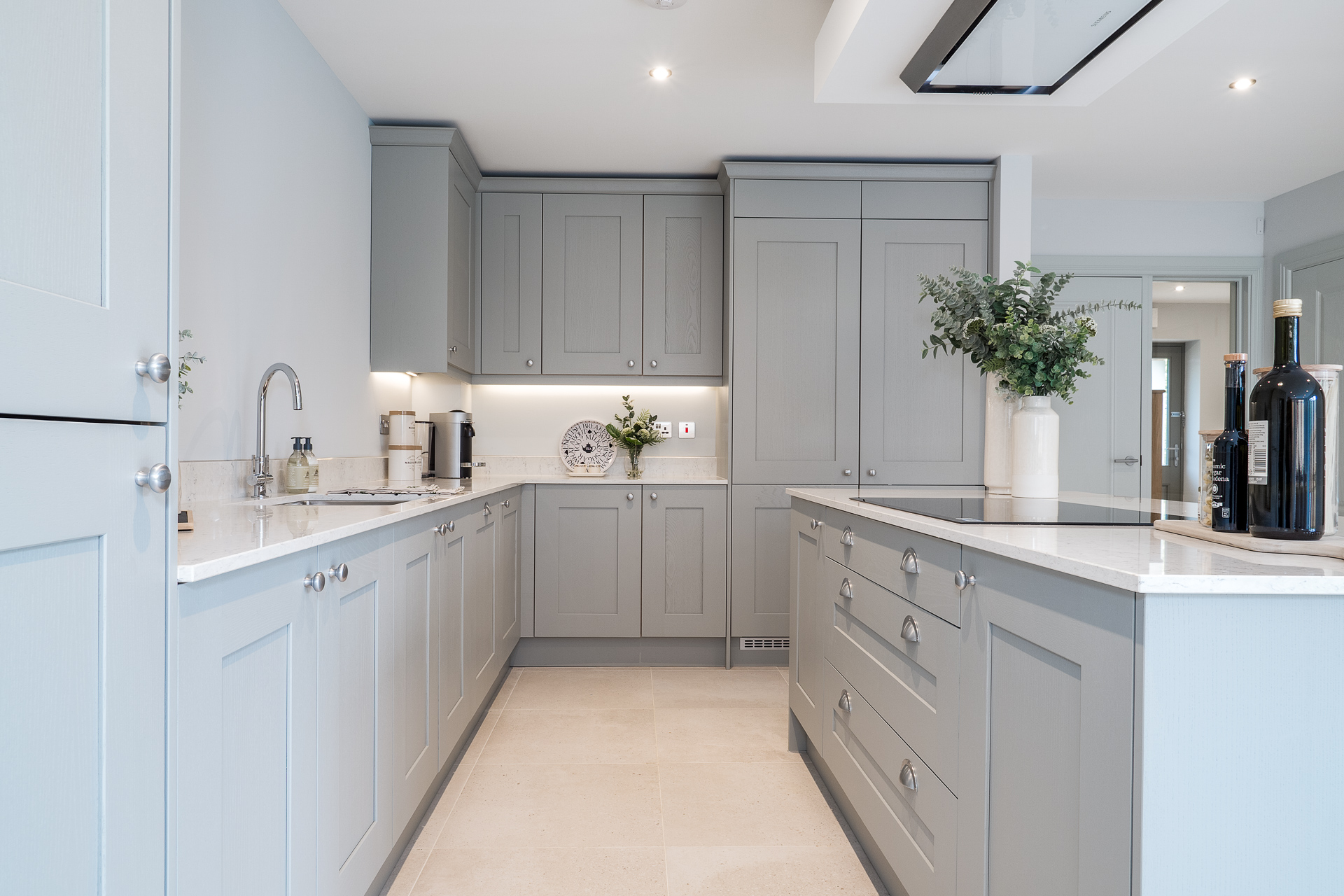 Light grey kitchen with white countertop and silver hardware