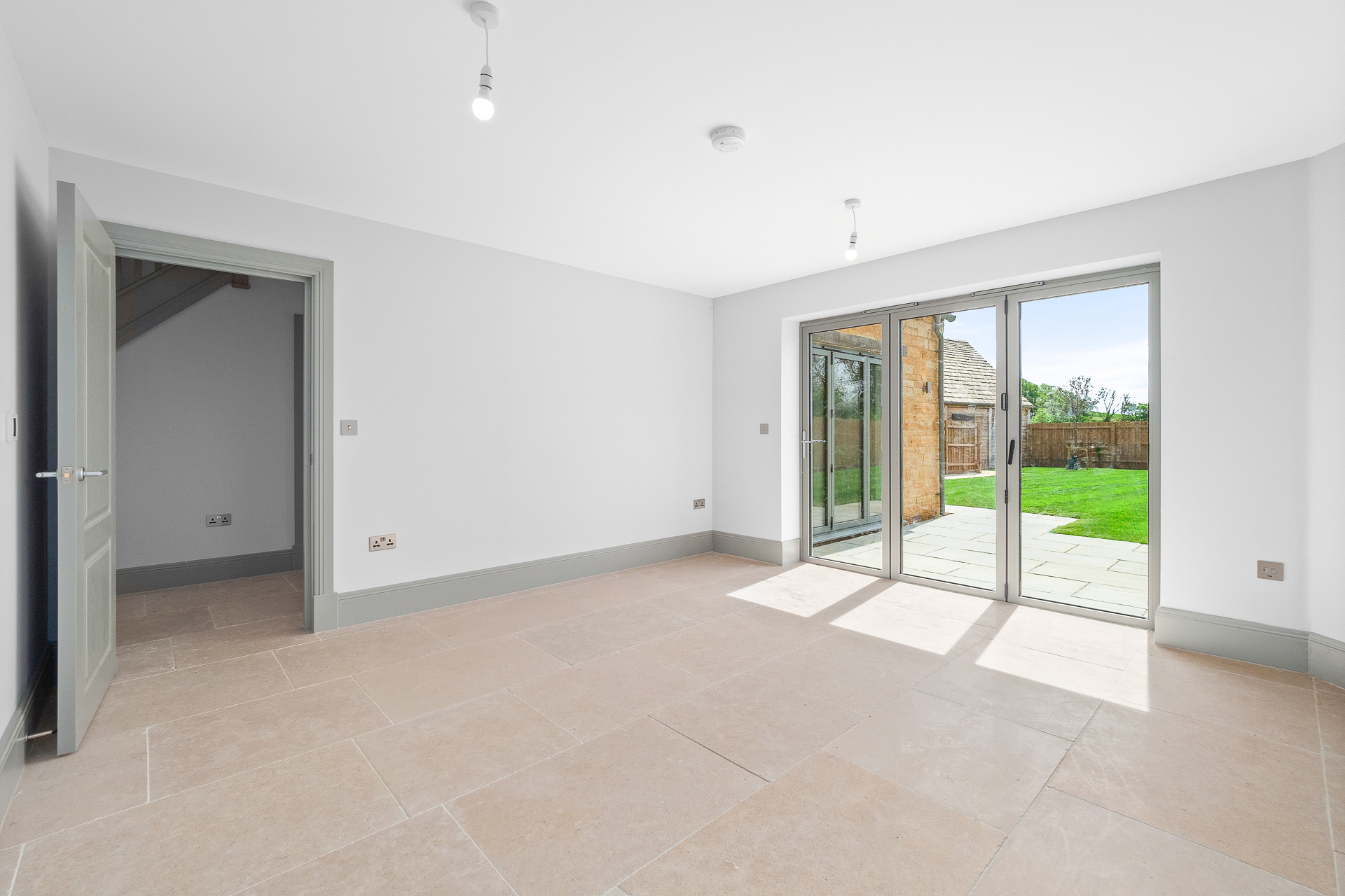 Empty room with tiled floor, grey door and windows and patio door