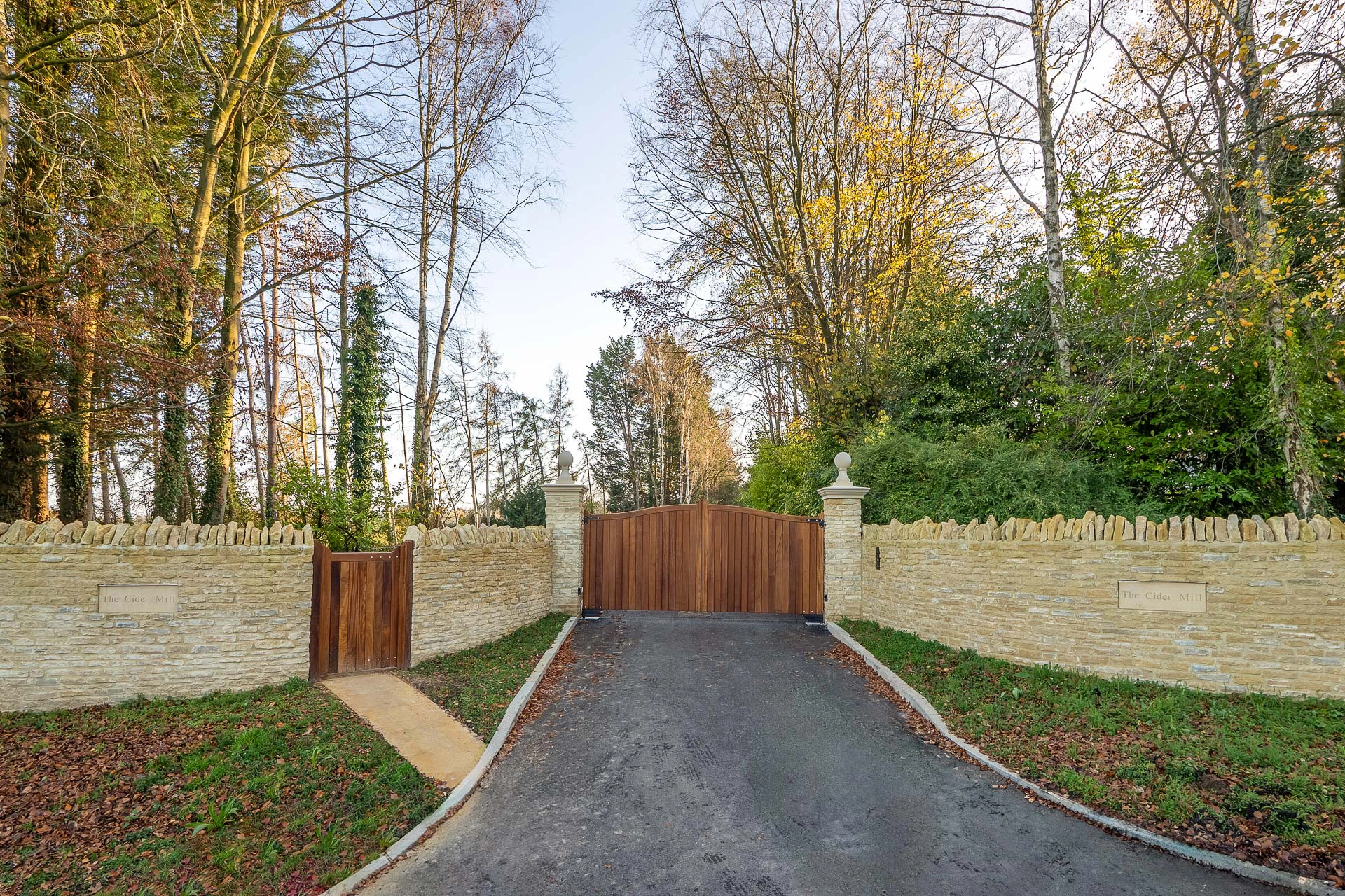 Large brown gate with brick wall either side