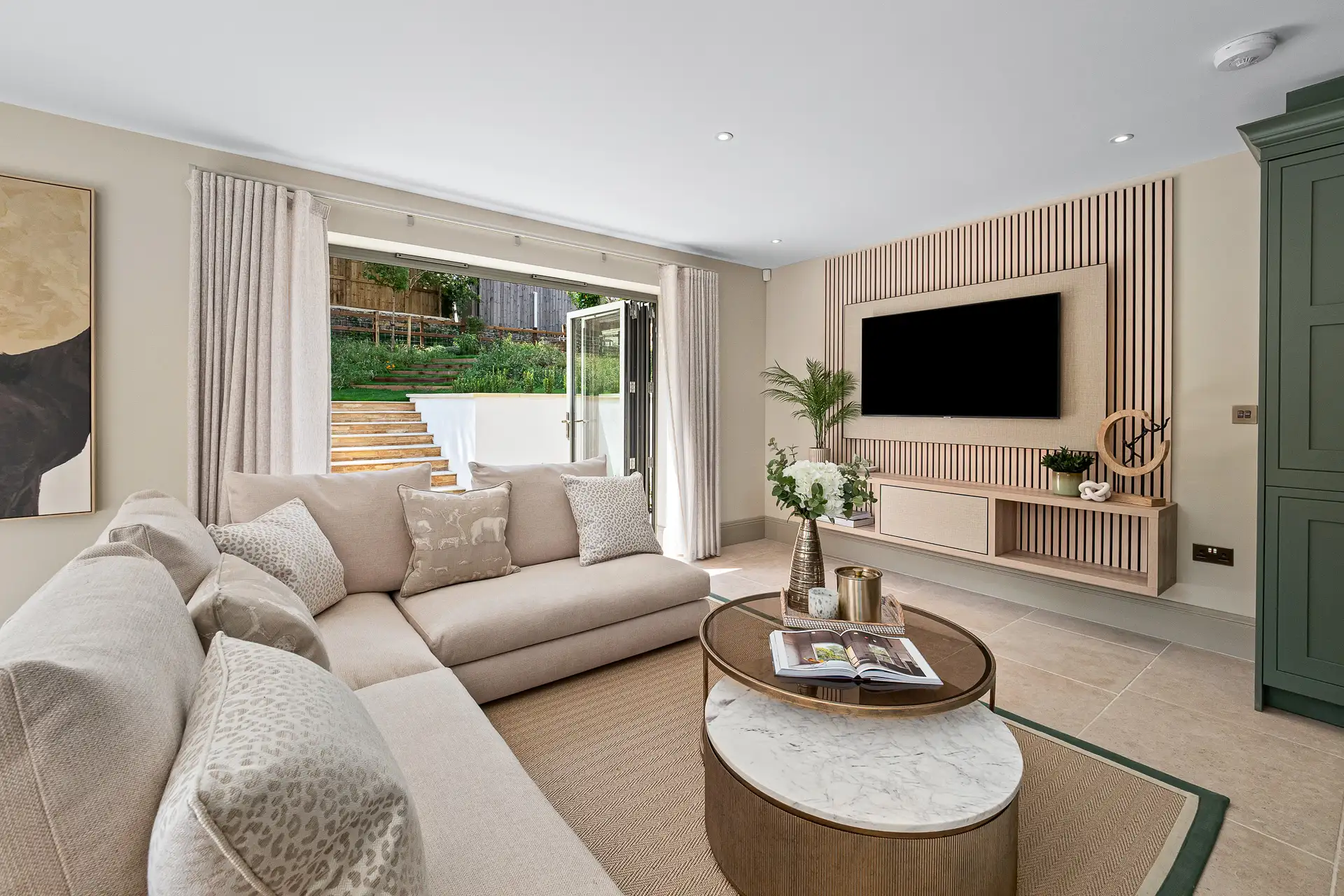Living room with acoustic panelling around the TV and patio doors leading to the garden