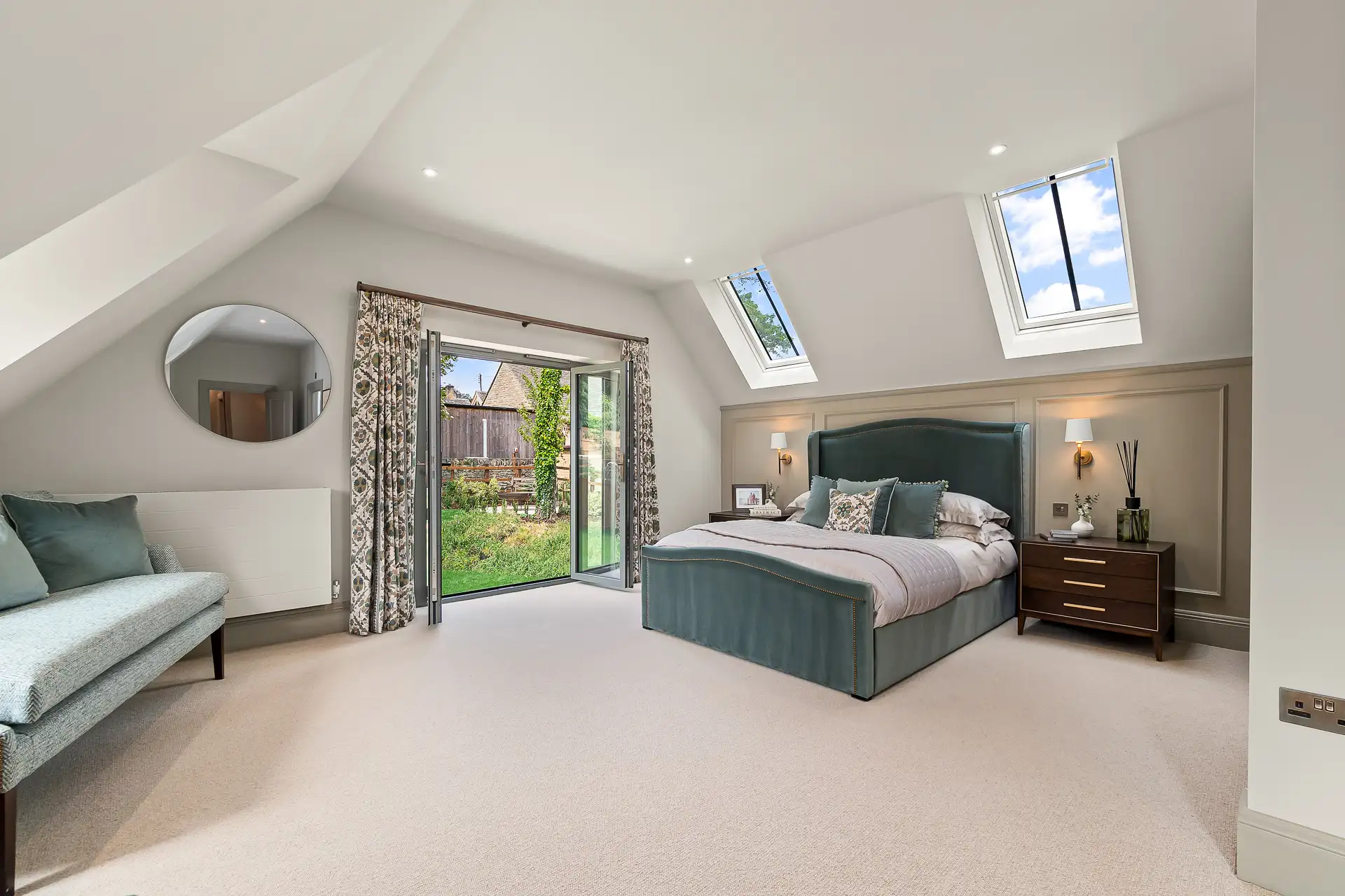 Large bedroom with green velvet bed and patio doors leading to garden