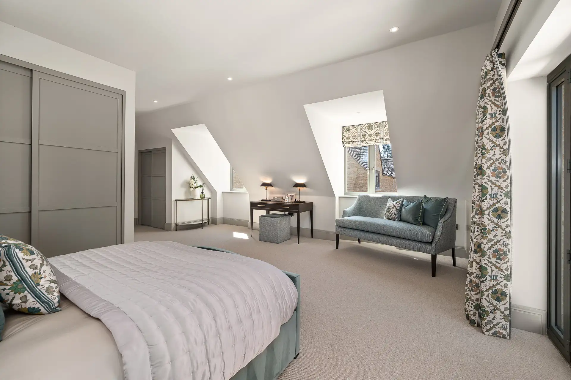 Bedroom with built in wardrobes, patio doors, two large windows and blue chair