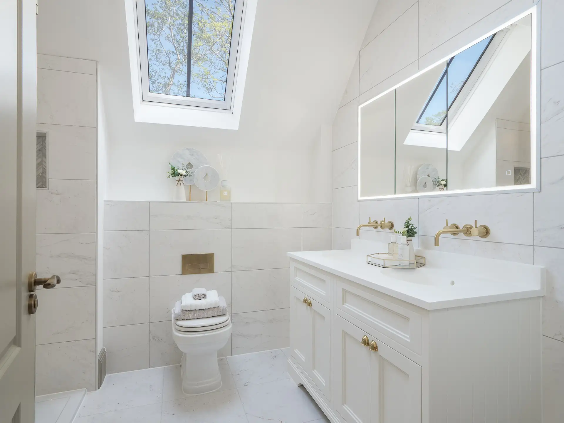 White marble bathroom with white under sink unit with gold hardware