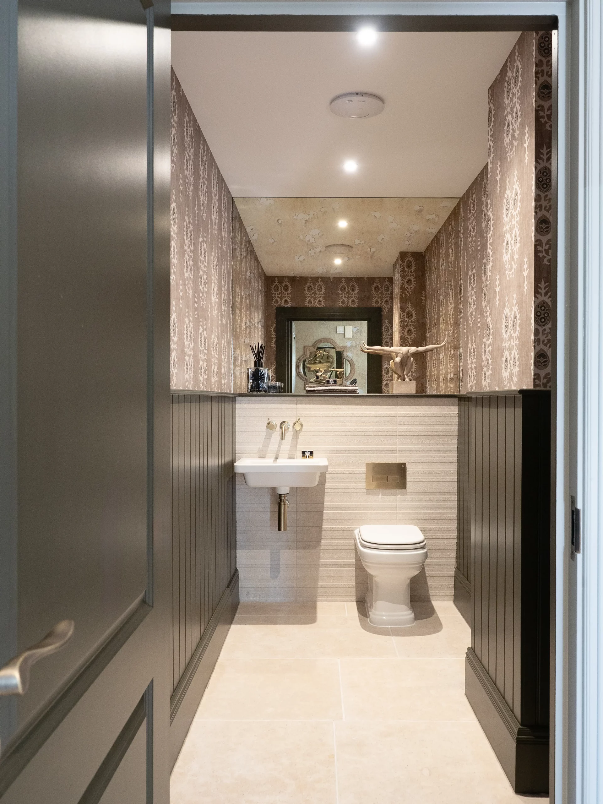 Downstairs bathroom with decorative wallpaper, mirror wall and black door