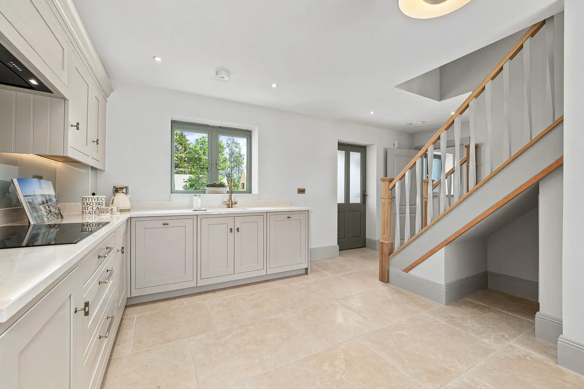 Kitchen with tiles and beige cupboards and light grey stairs