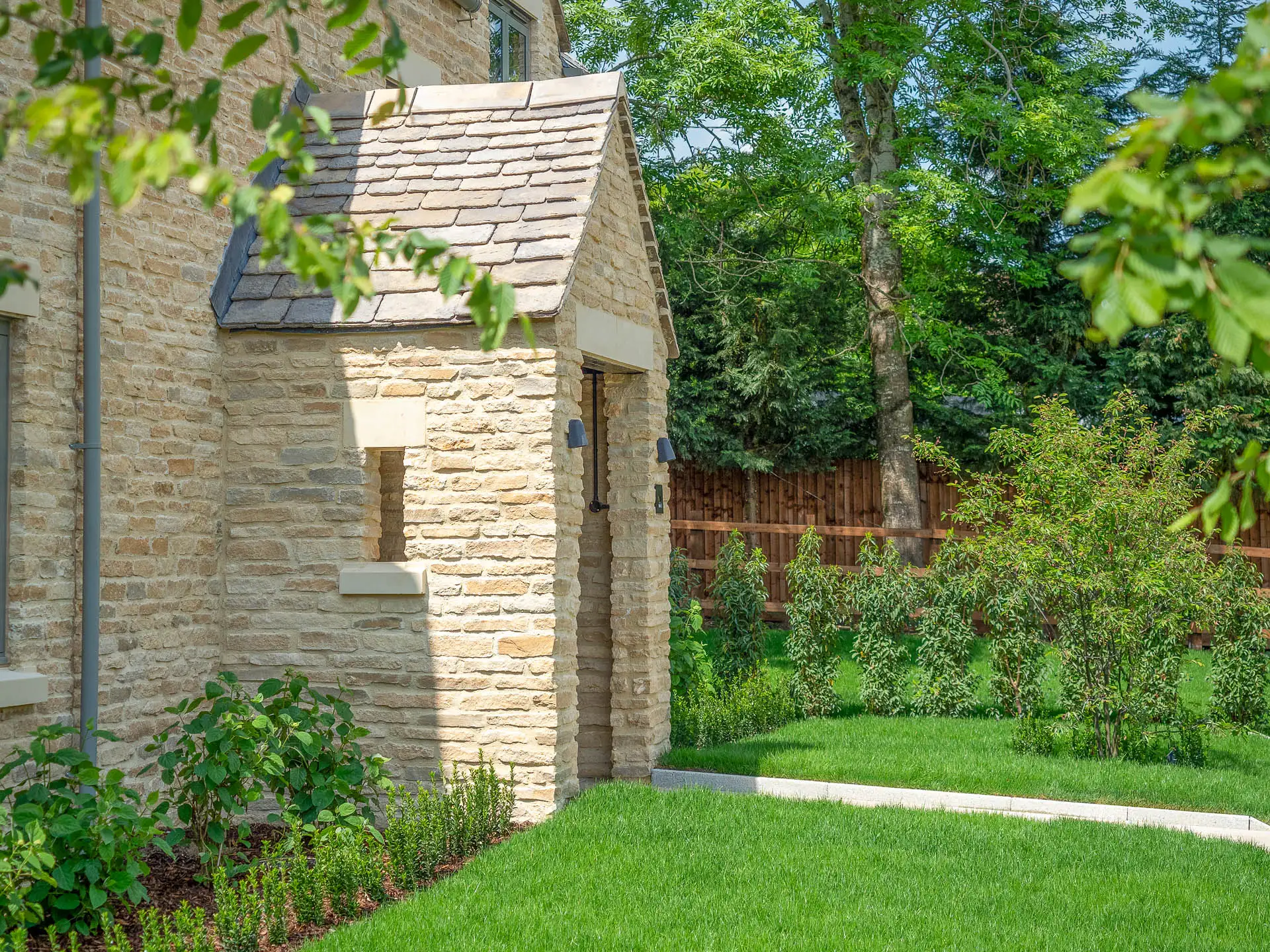 Beige brick canopy entrance to house, grass front garden with pathway