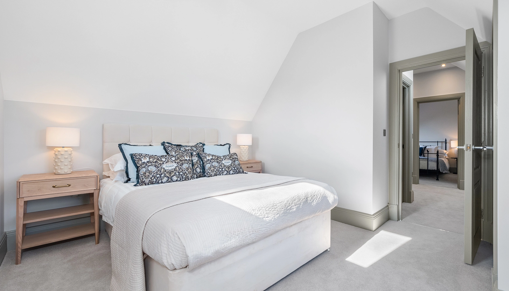 Grey doors with bed in the middle of teh roon and wooden bedside tables