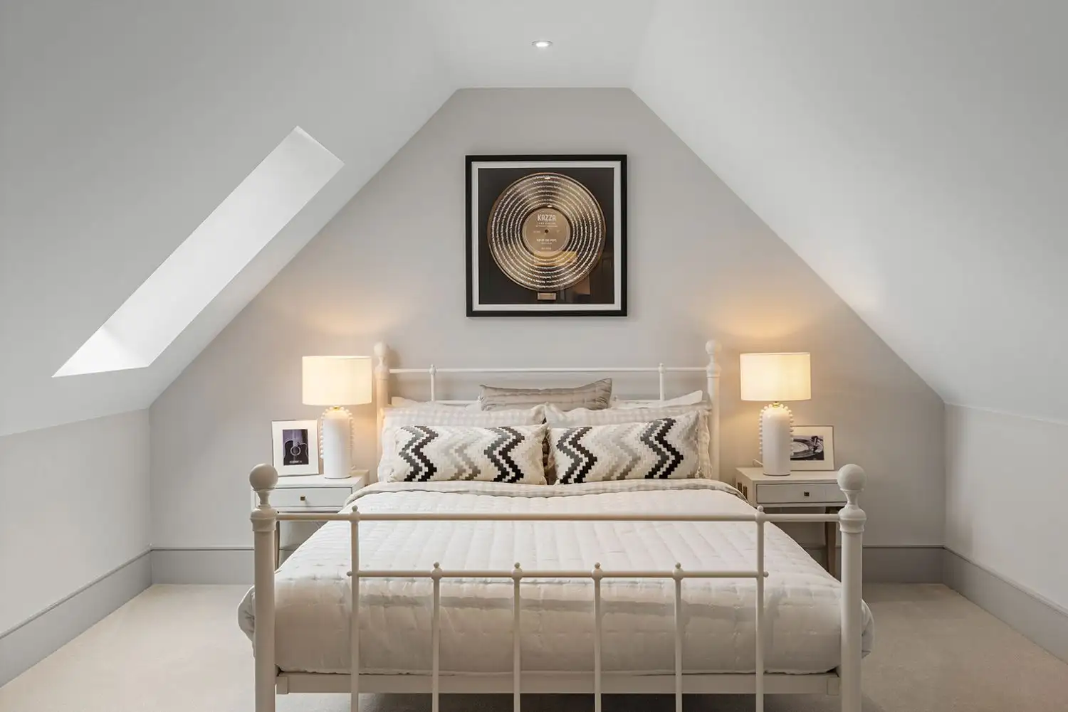 Bedroom with slanted roof both sides and a white metal bed