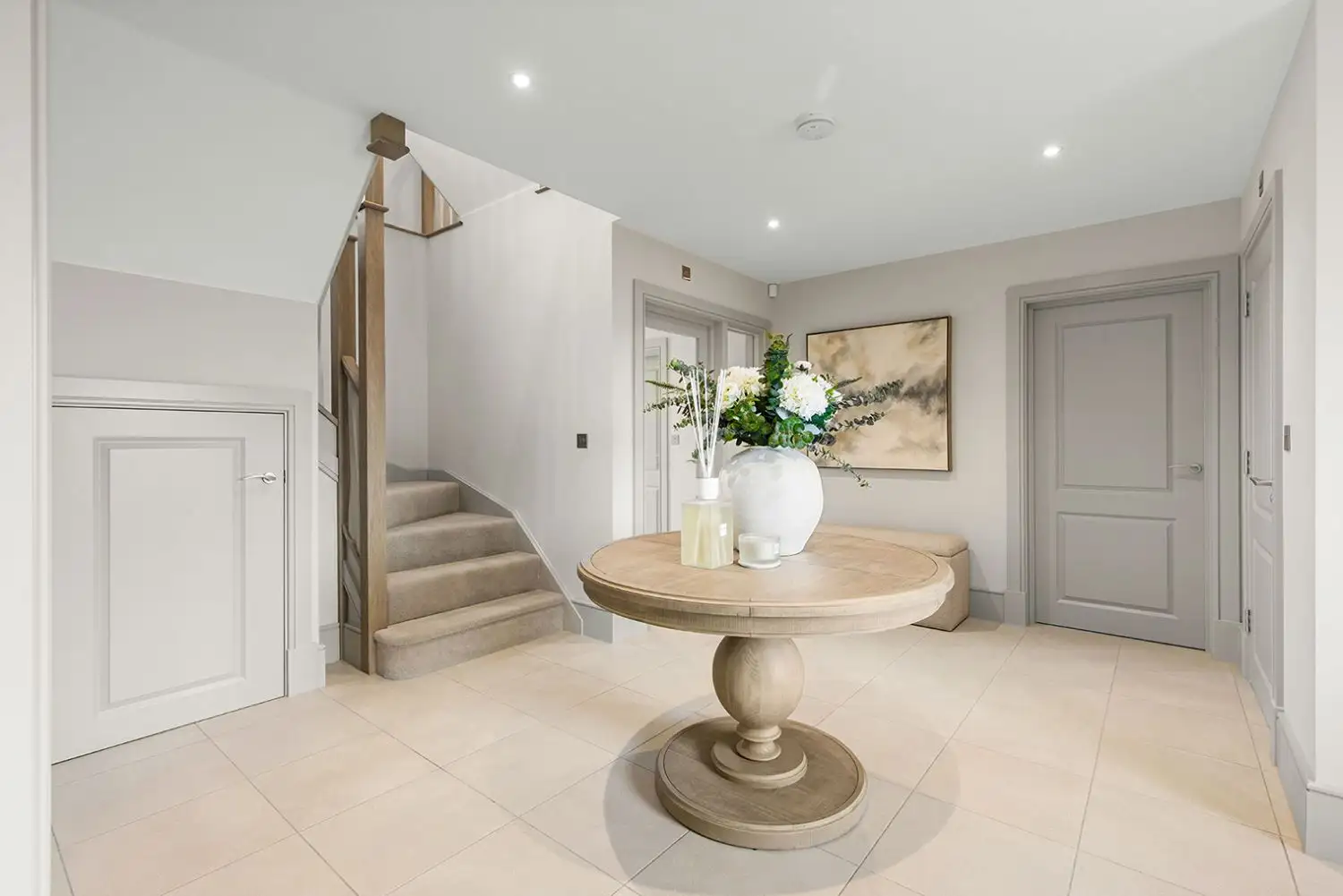 Entrance of a house with stairs, round table and light grey doors
